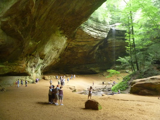 park visitors looking like ants beneath a large waterfall