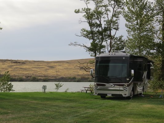 a Class A parked in a field near some water