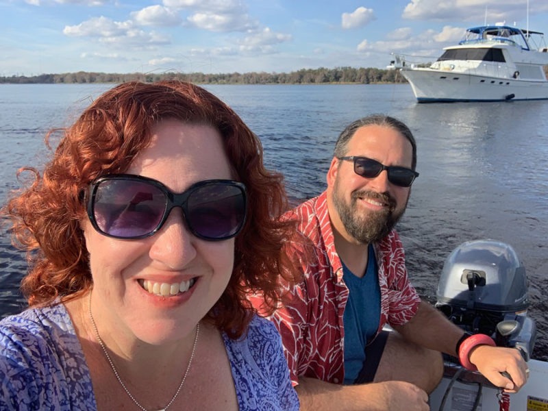Chris and Cherie on a dingy, their motor yacht in the background