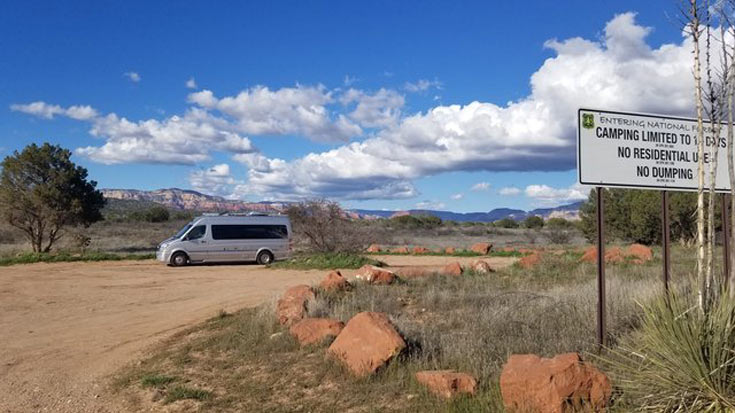 a silver van converted into an RV by Airstream camping in the desert