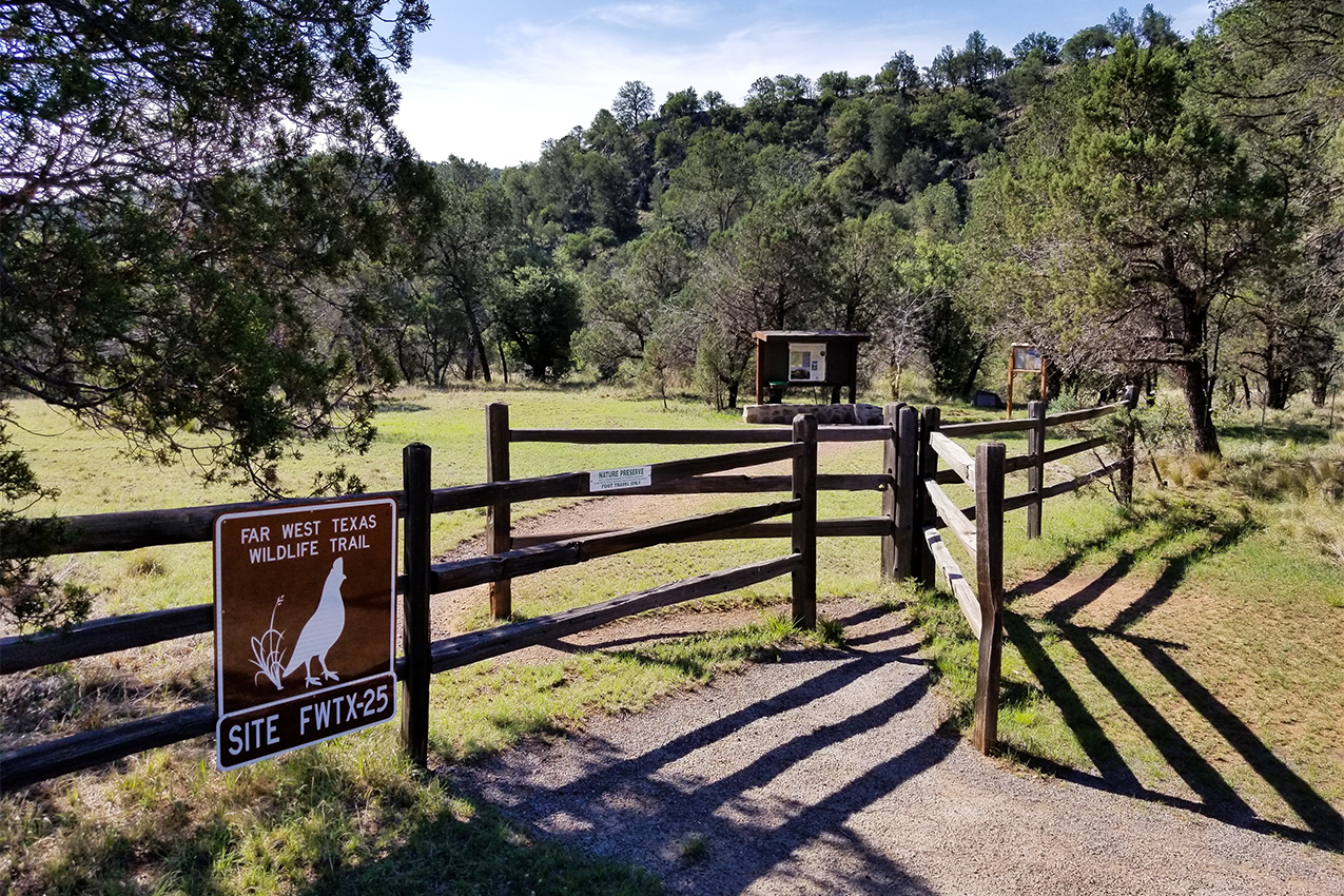 Trailhead with a wooden fence and sign.