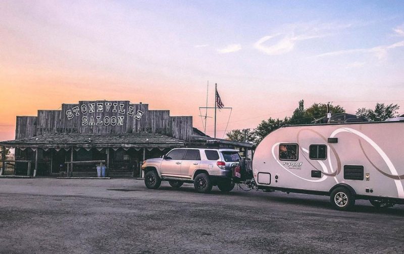 a 4runner pulling a travel trailer, parked outside of a biker bar in Montana