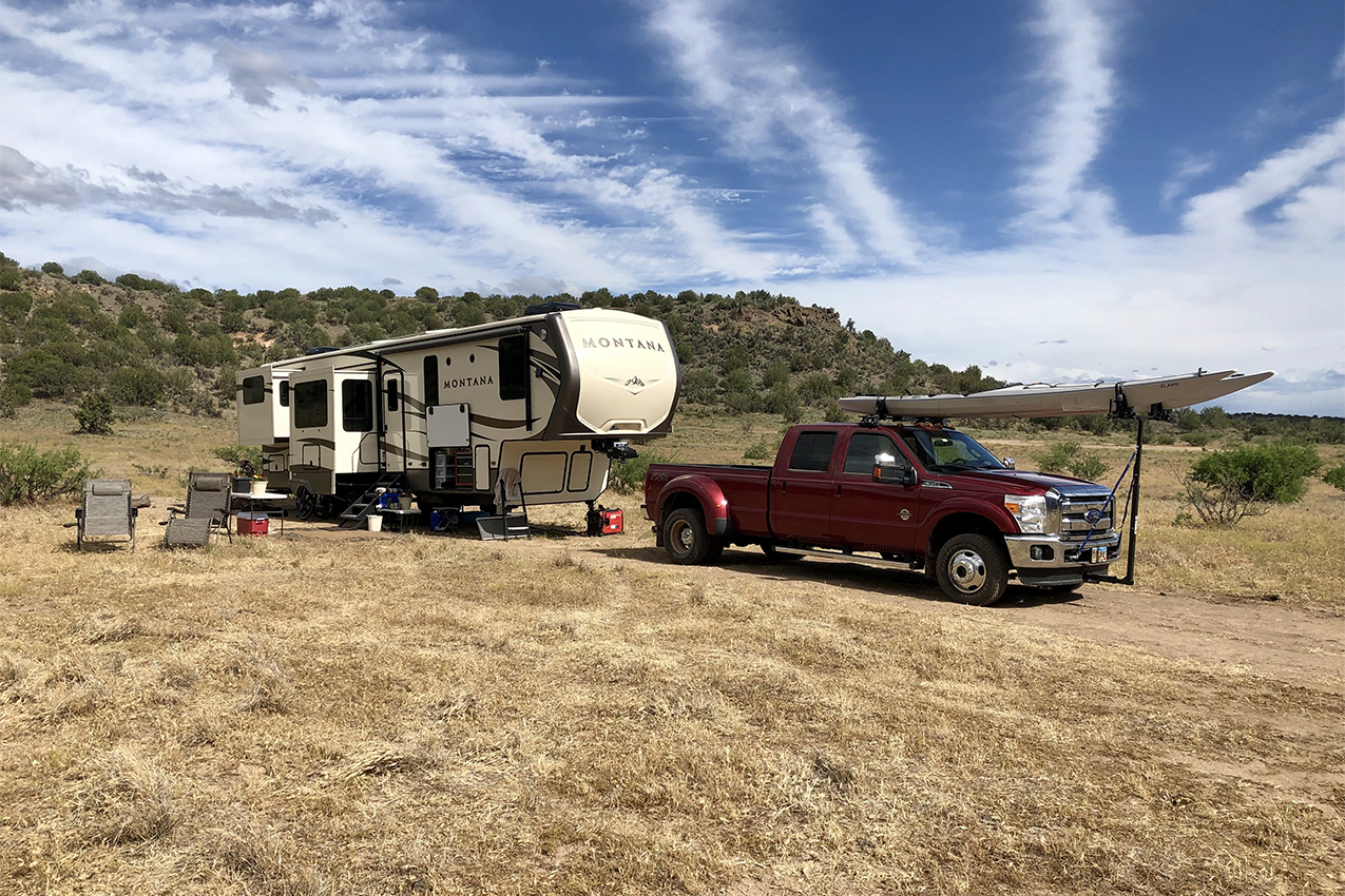 Truck and fifth wheel camped in forest.
