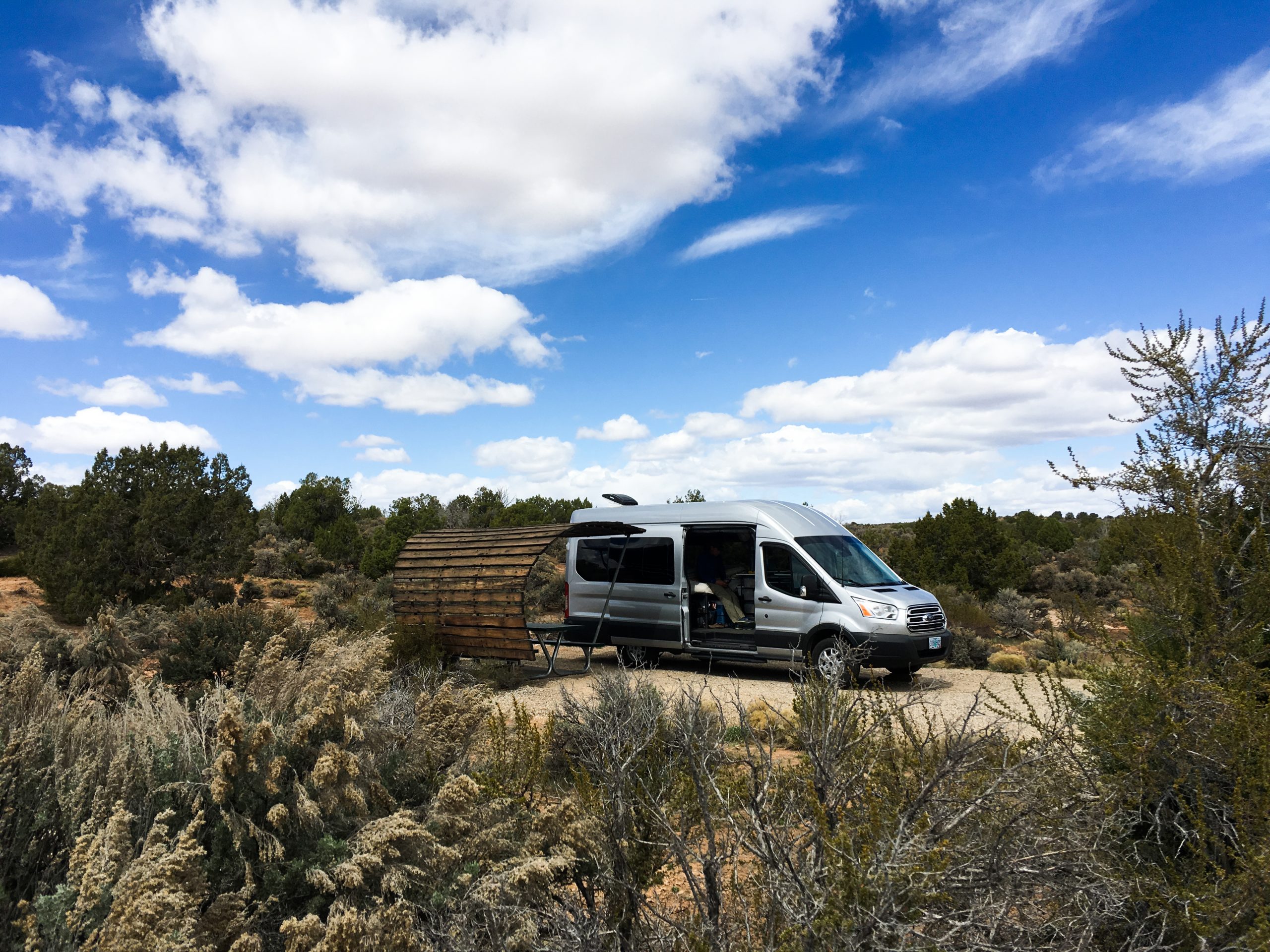 Van parked next to a shade structure in the desert.