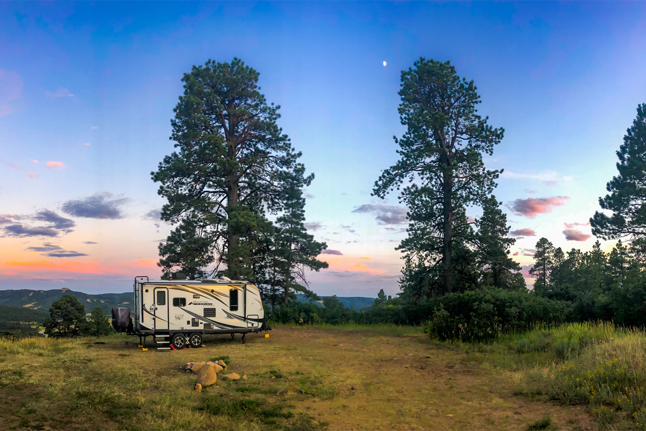 RV parked in the woods at sunset.