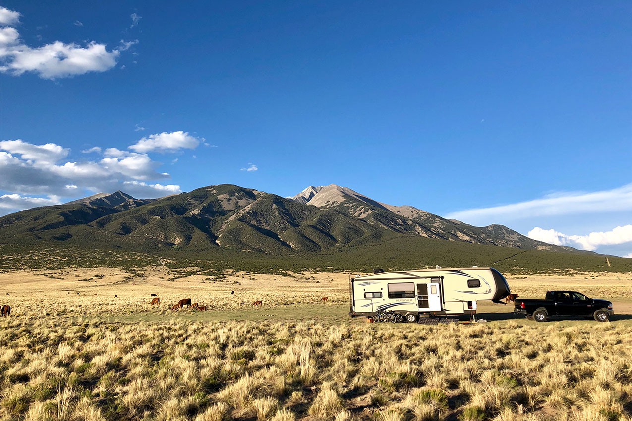 Truck and fifth wheel parked in front of a mountain.