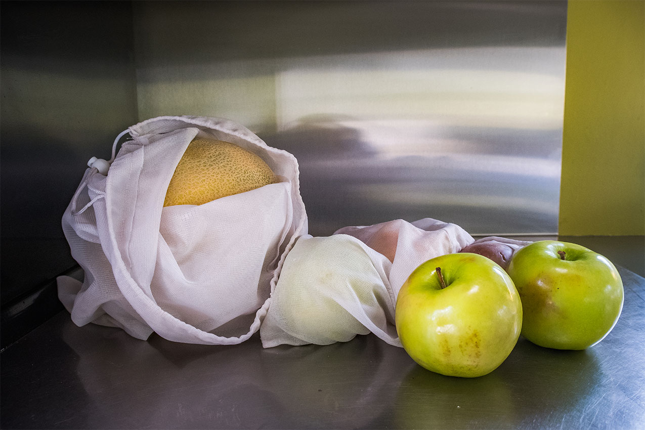Reusable mesh vegetable bags with fruit in them.
