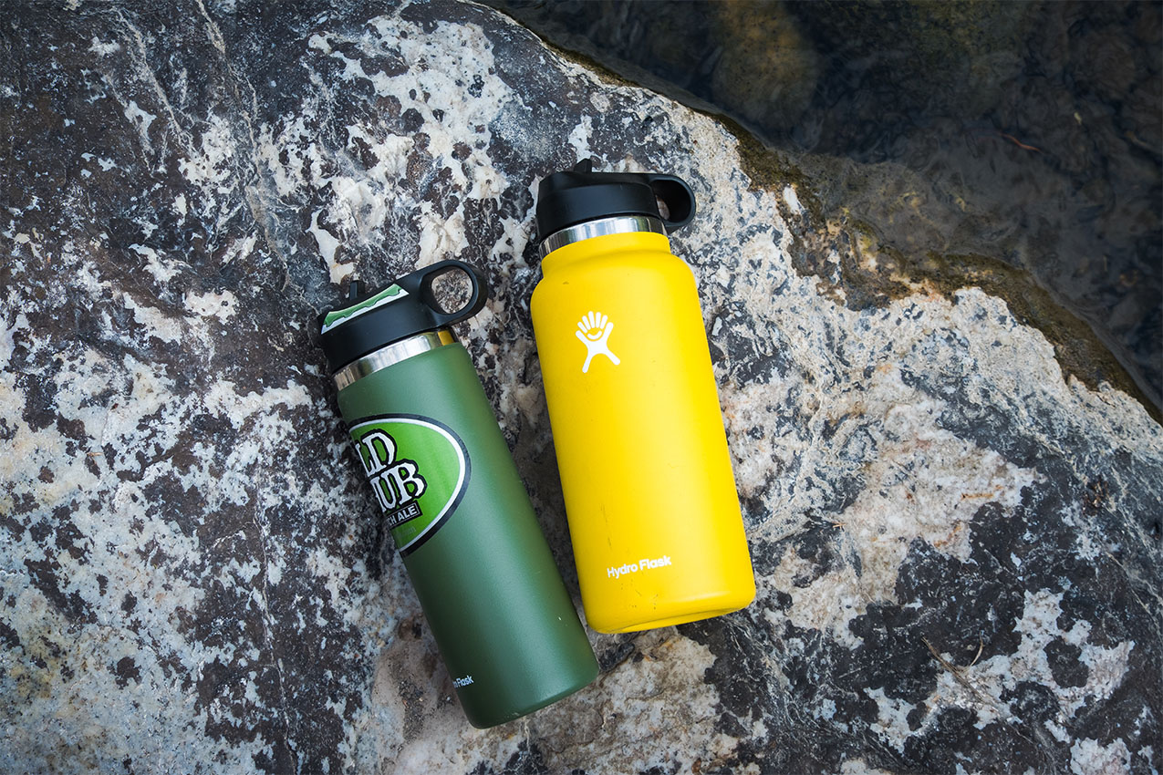 Green and yellow water bottle on a rock next to a creek.