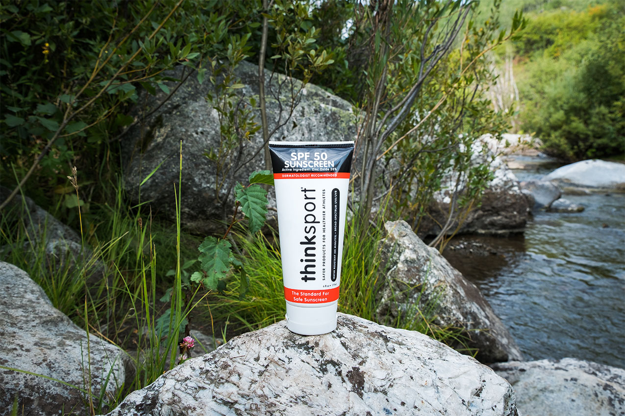 Think Sport sunscreen on a rock by a creek.