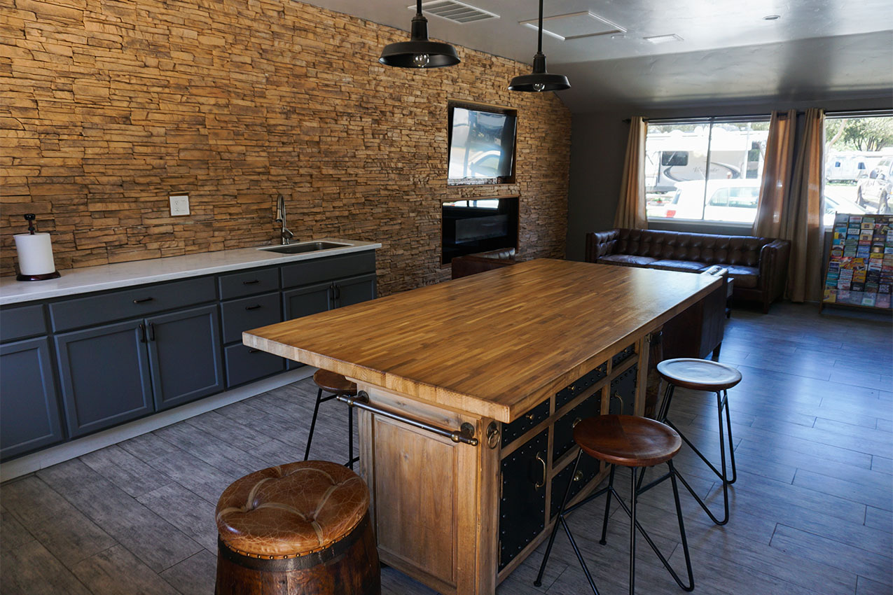 Wooden island with stools around it in a common space.