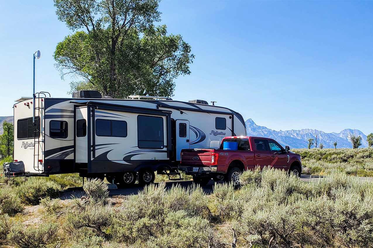 Red truck parked next to a travel trailer surrounded by sage