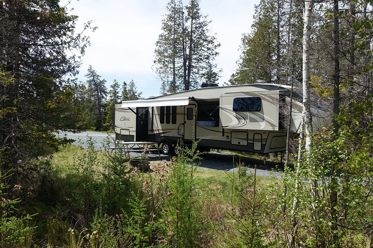 Fifth wheel RV nestled in the woods at a campground.