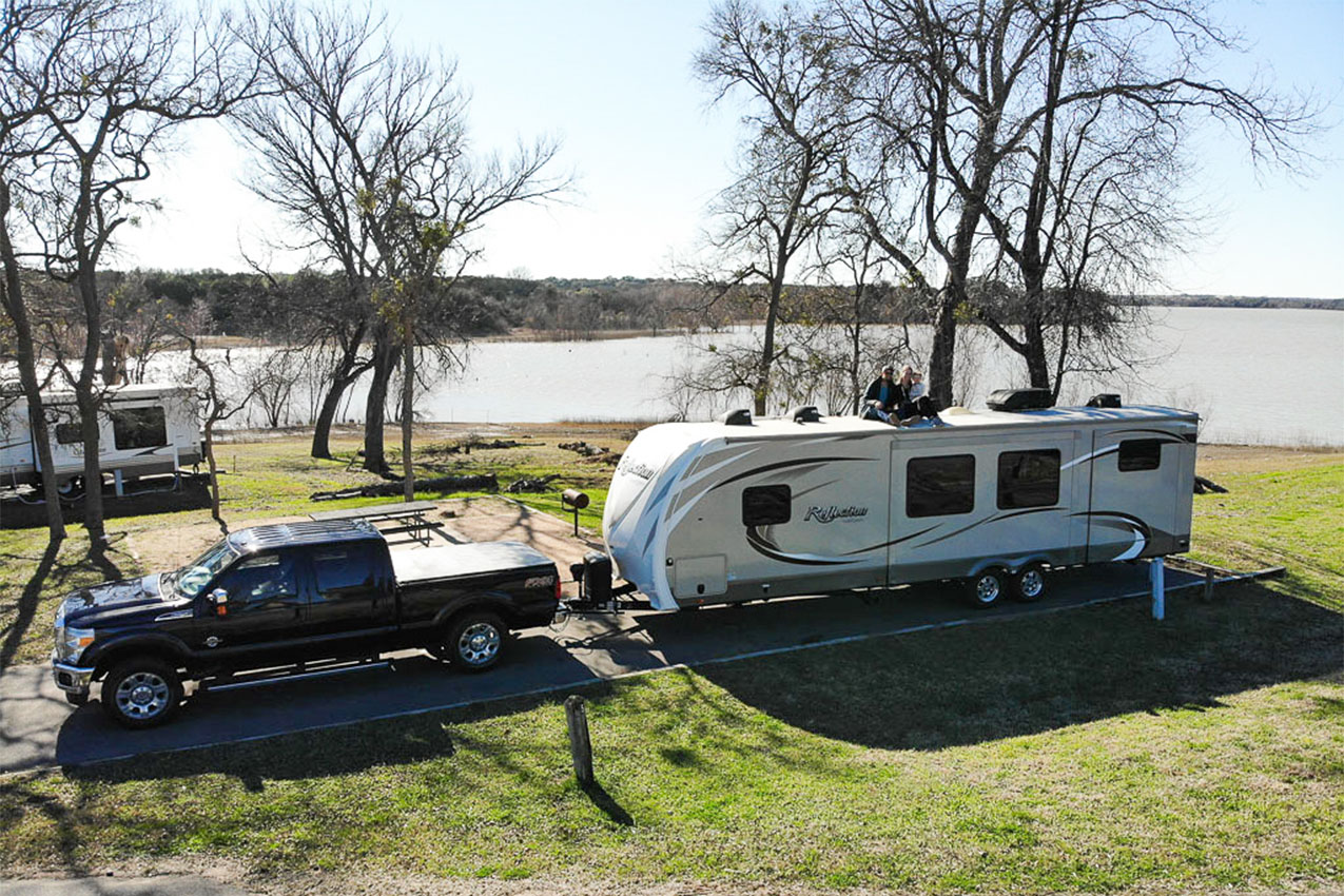 Truck and RV parked in a campground by a lake.
