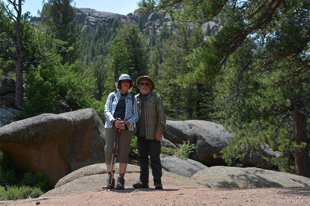 A couple standing in front of rocks and trees.