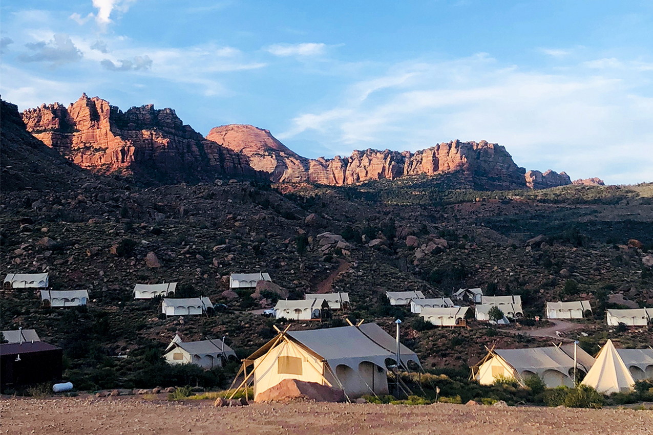 Several canvas tents scattered across red rocks in Zion.
