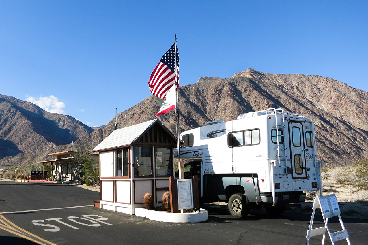 Truck camper pulled up at a state park campground entrance.
