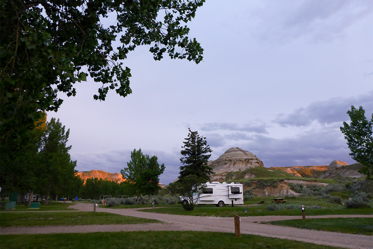 Single RV parked at a campground under a purple sky.
