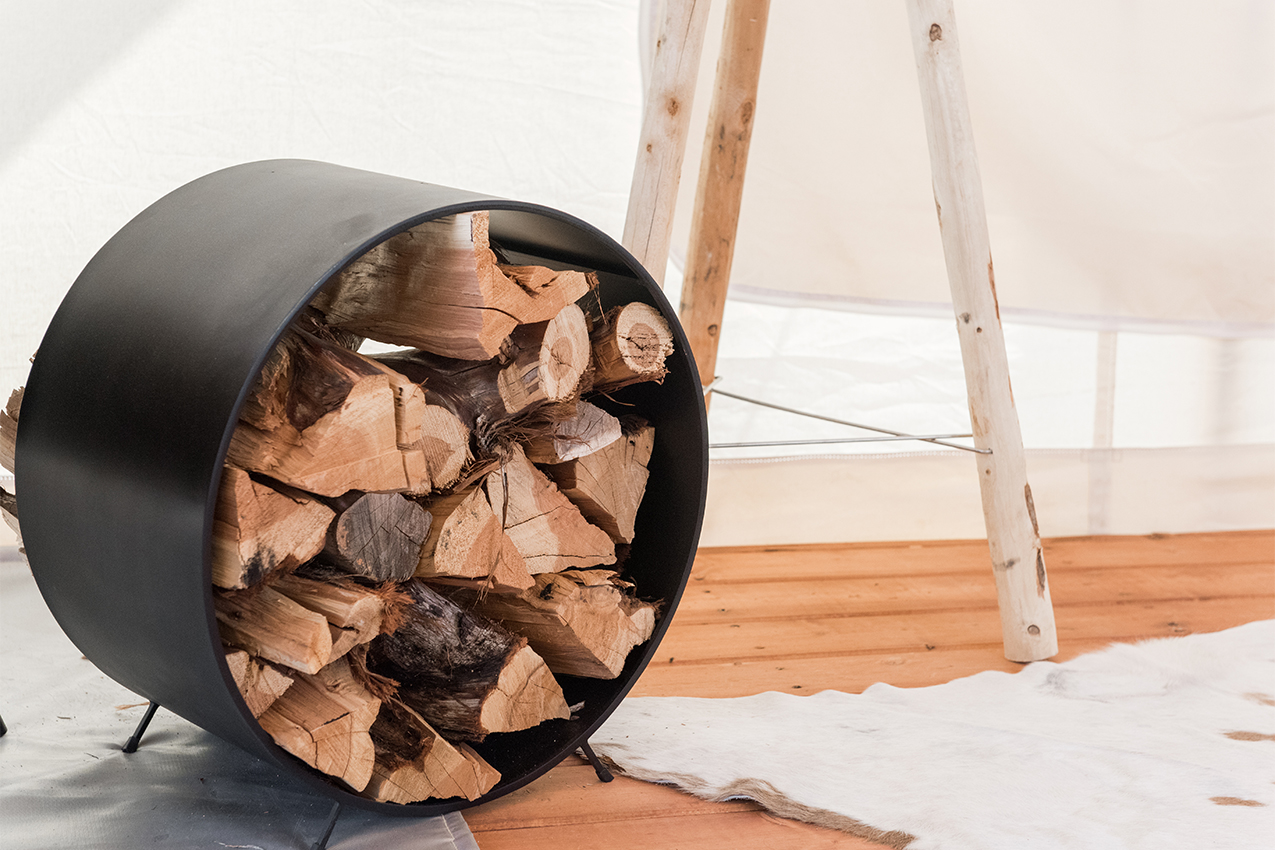 Round metal wood rack and white rug on a wooden floor.