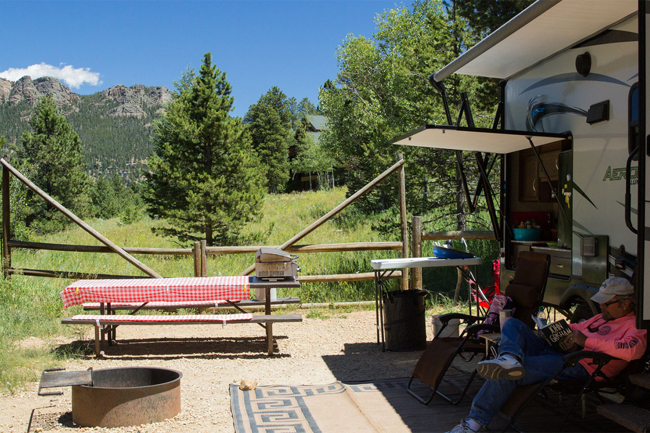Man sitting outside his RV by a picnic table.