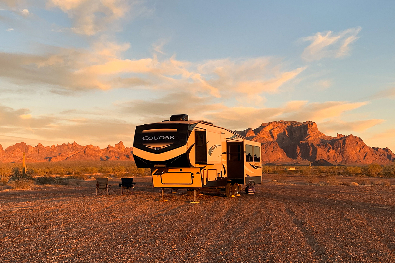Fifth wheel parked in the middle of the middle at sunset.