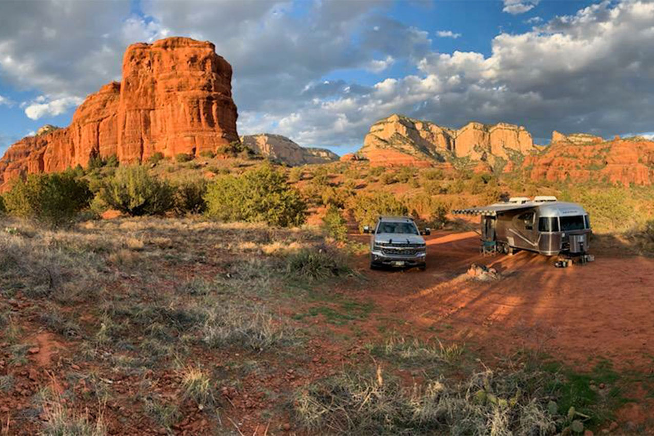 Truck and RV parked amongst red rocks in the desert.