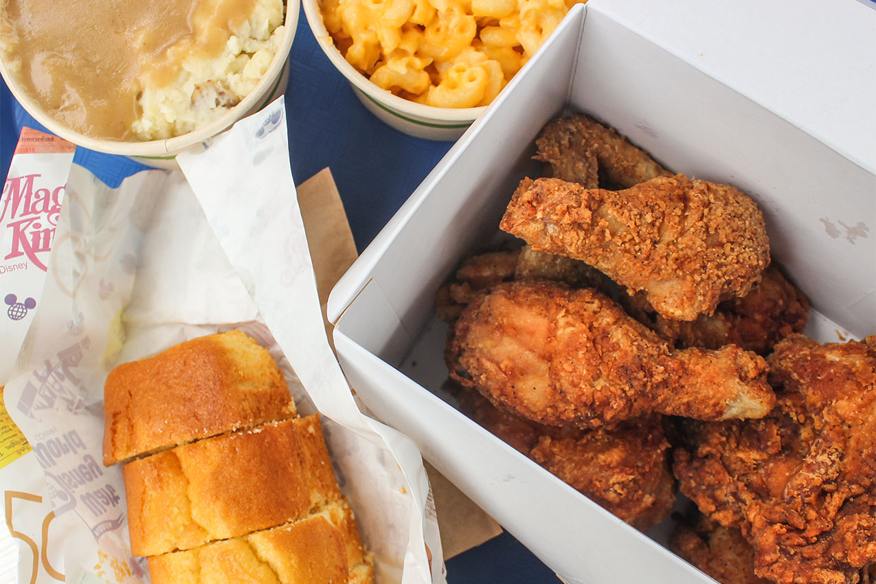 Tray of fried chicken, French bread, macaroni and cheese, and mashed potatoes and gravy.