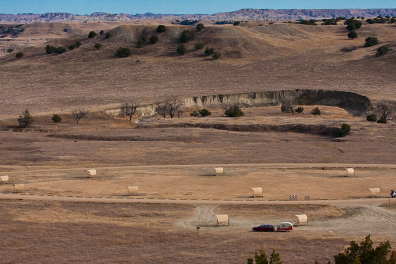 A lone RV parked in a large field with several picnic pavilions.