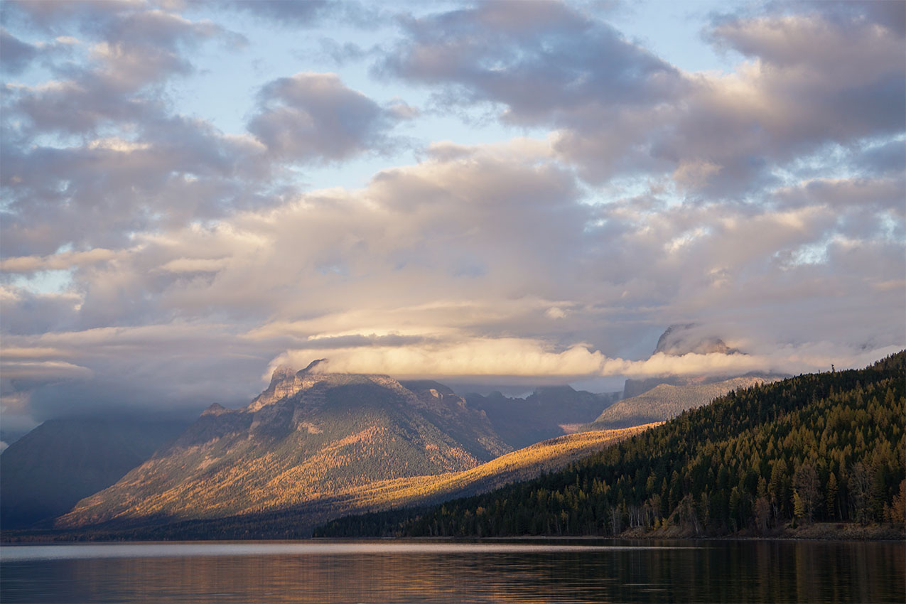 Cloud covered mountains next to a lake.