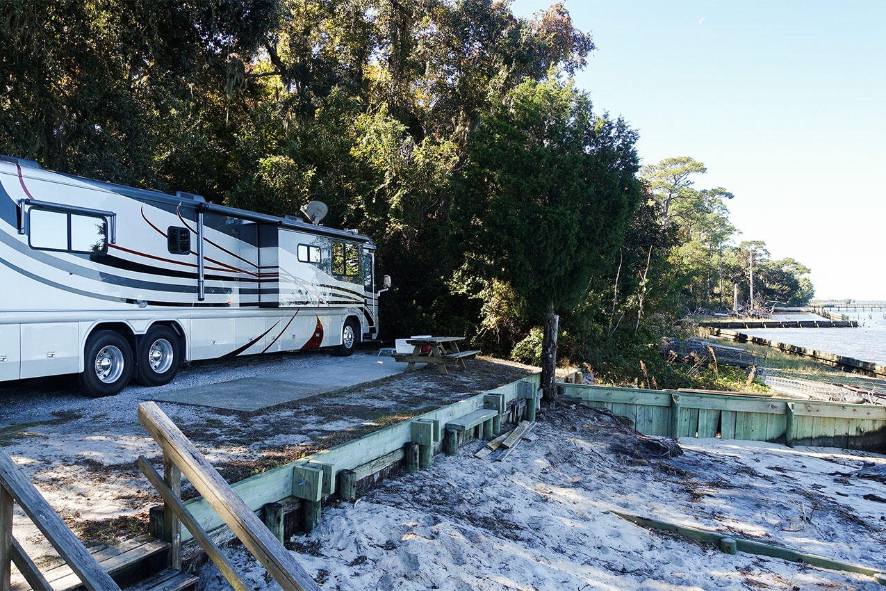 Class A in a campsite next to the beach and ocean.