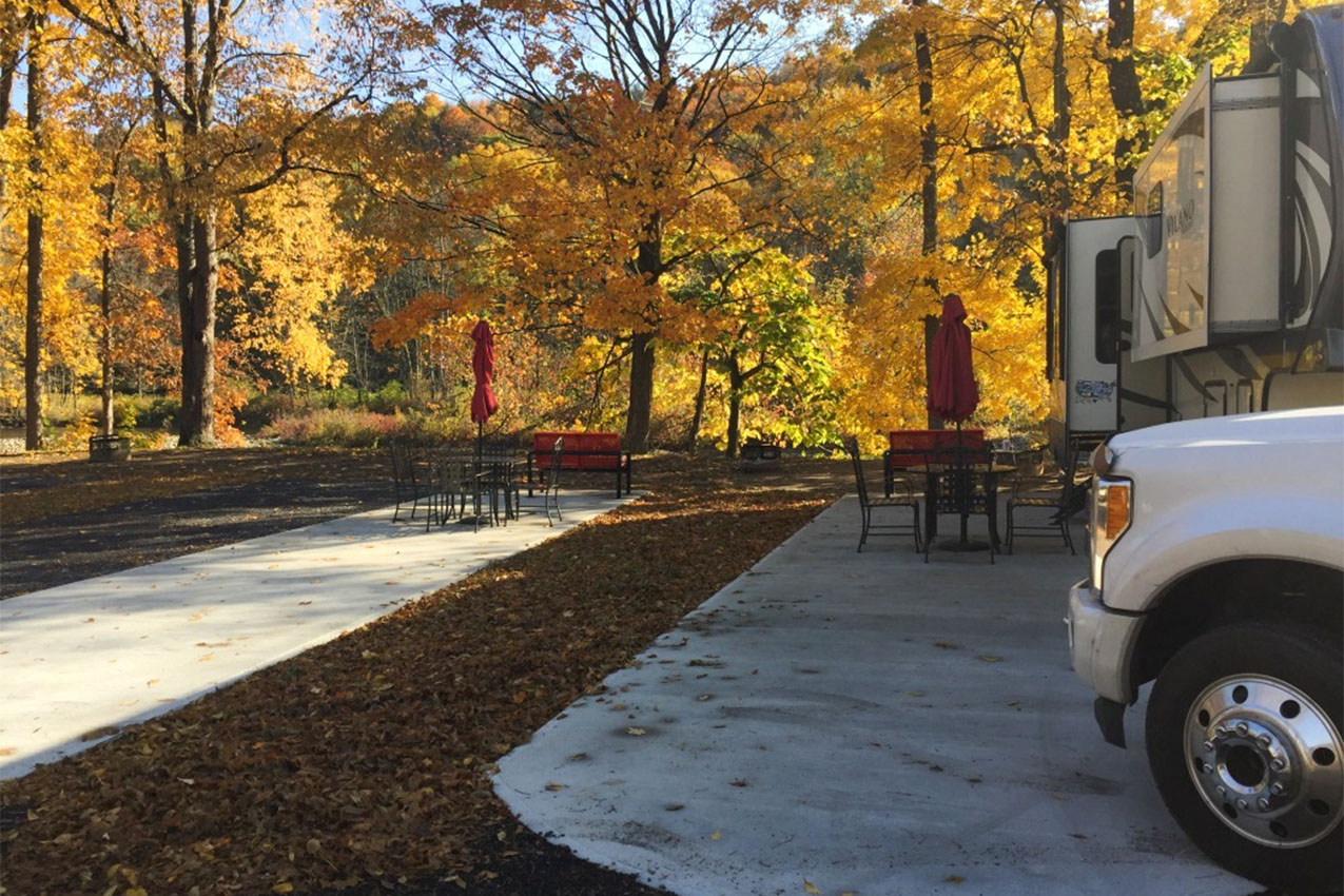 Concrete patio pads next to gravel RV site at a campground.