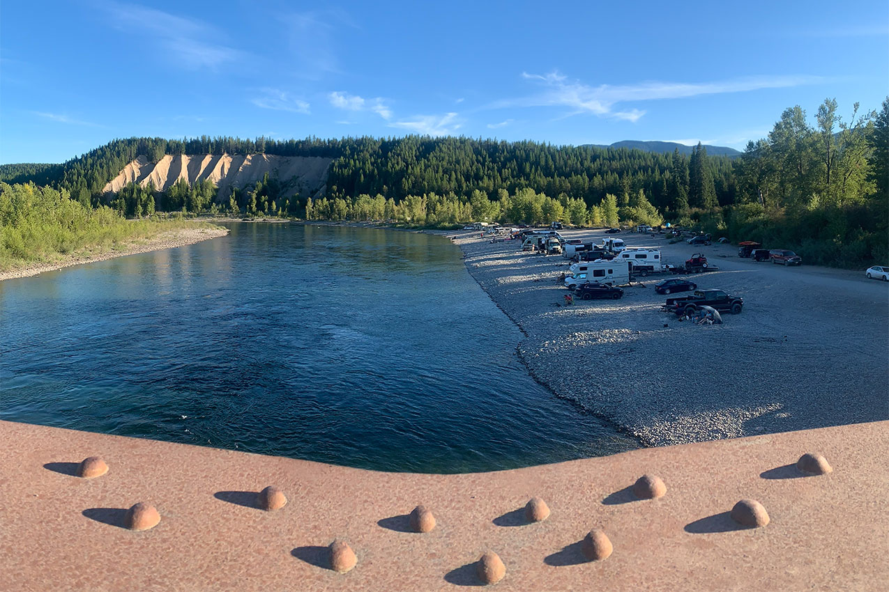 View from a bridge overlooking river and RVs parked along the shore.