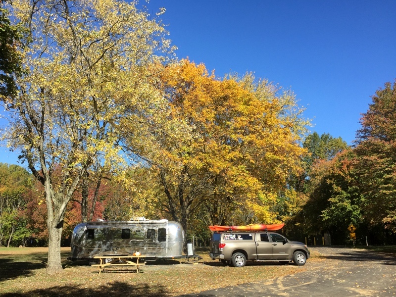 Truck pulling an Airstream trailer in a fall foliage wooded area