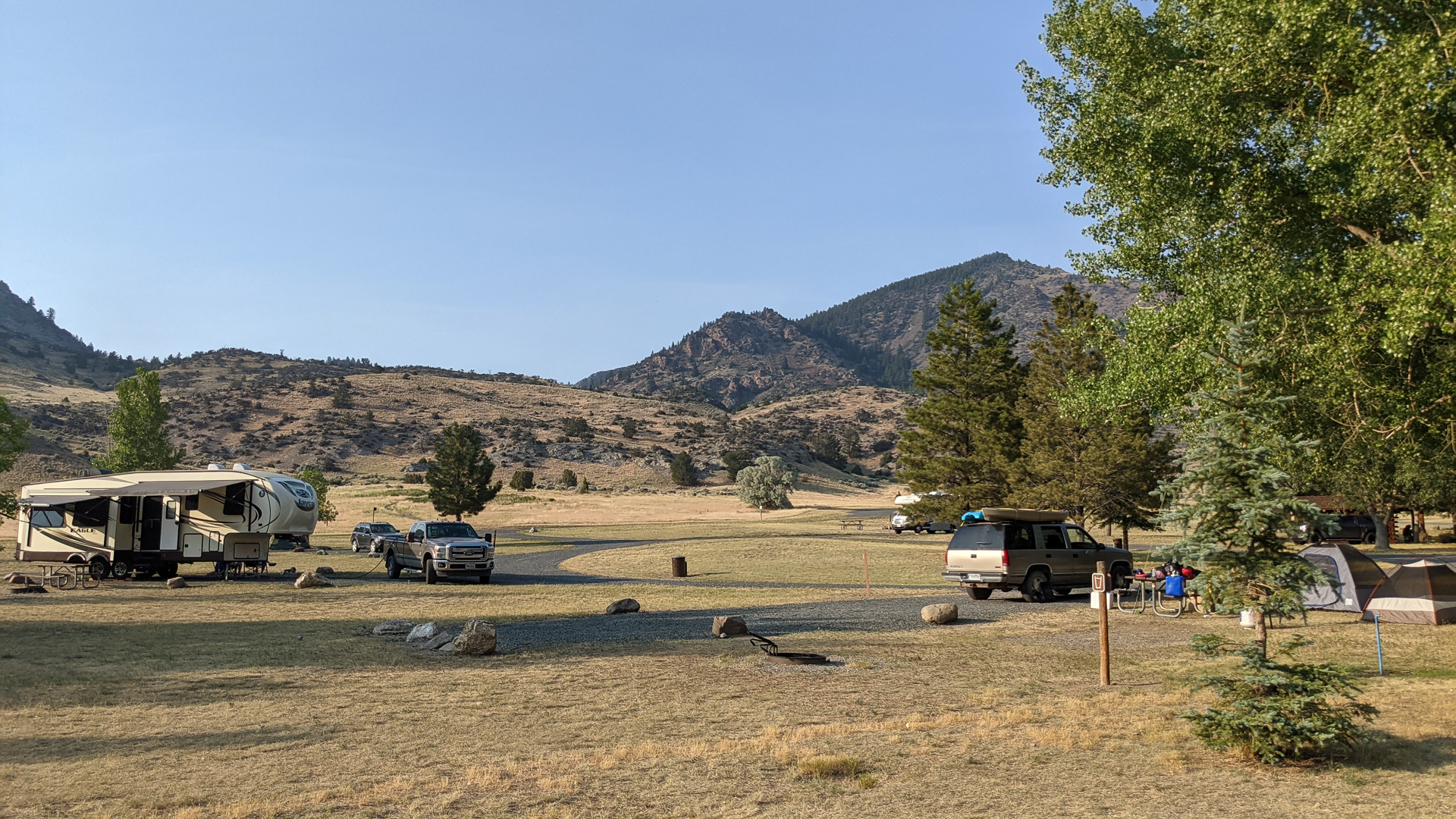 Wide angle view of grassy campground with RV and tent set up