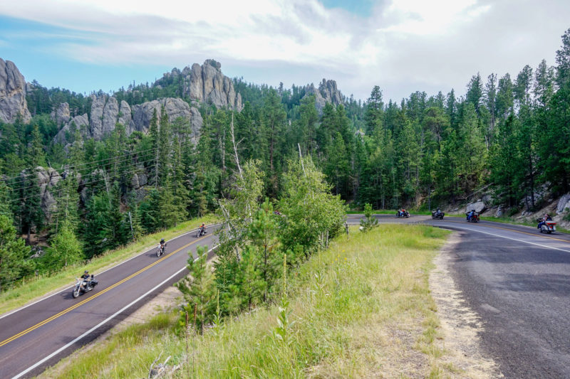 Sharp turn in mountains with line of motorcyclists riding
