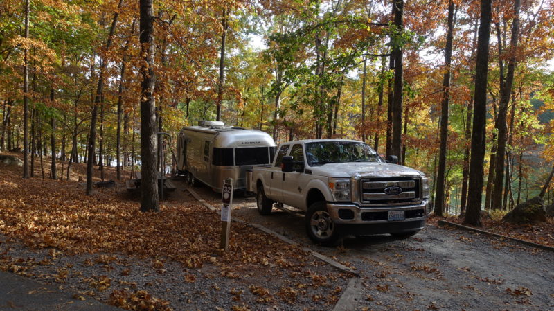 Truck pulling an Airstream RV through a wooded area