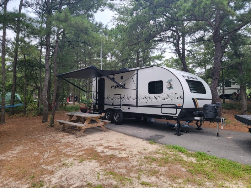 Travel trailer parked at a campground in Delaware in a wooded area.