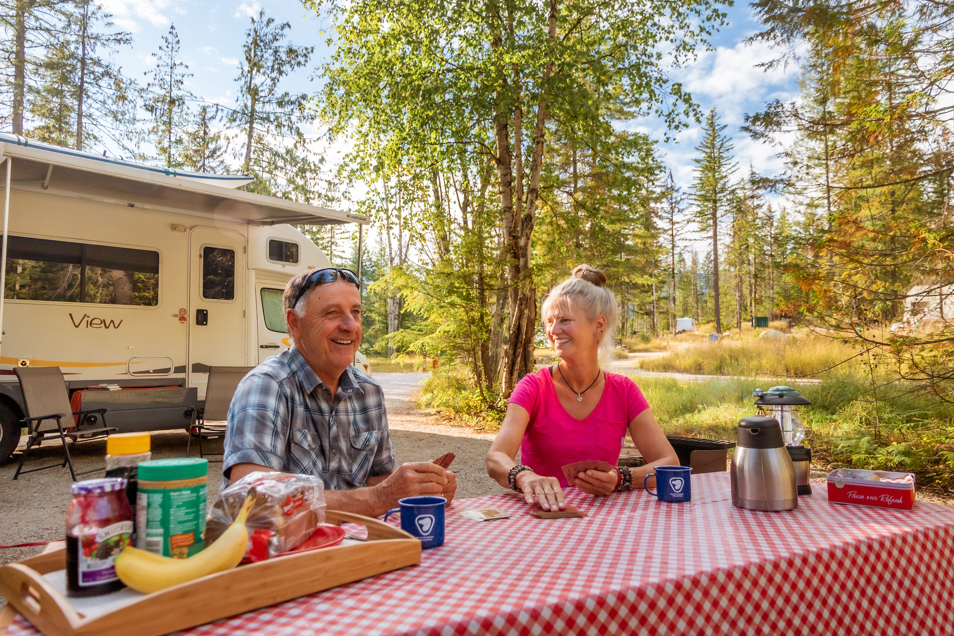 Couple playing cards at picnic table at campsite