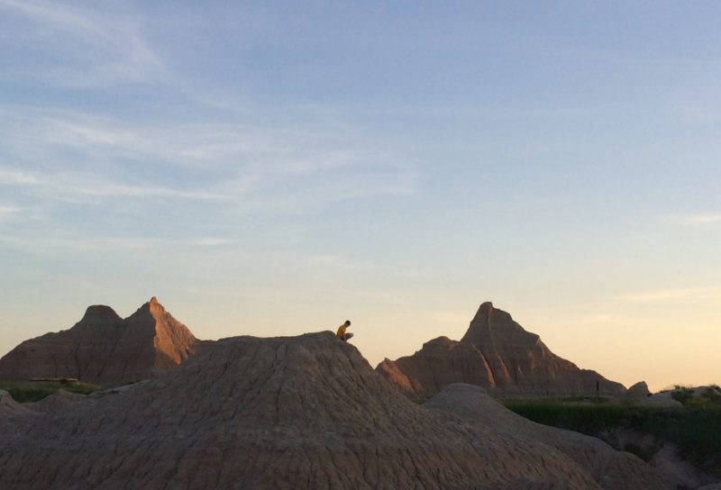 Child sitting on top of a large rock formation.