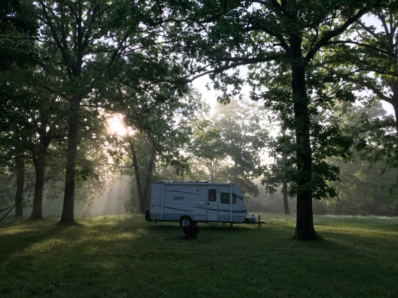 Travel trailer parked in a remote wooded area for camping.