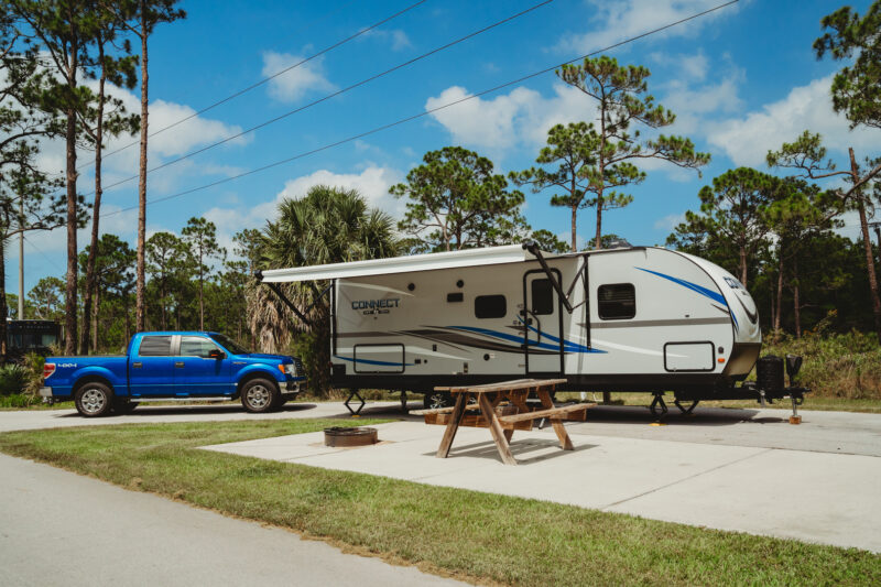 Trailer parked on concrete pad at campsite next to pickup truck