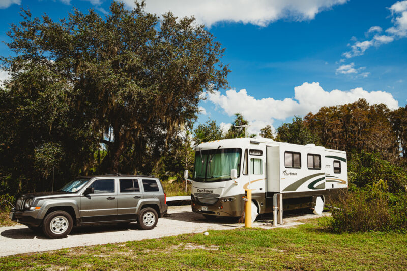 Motorhome parked at campsite with tow vehicle in front