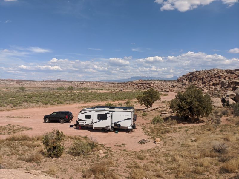 RV sitting on area with piles of rocks and mountains in background