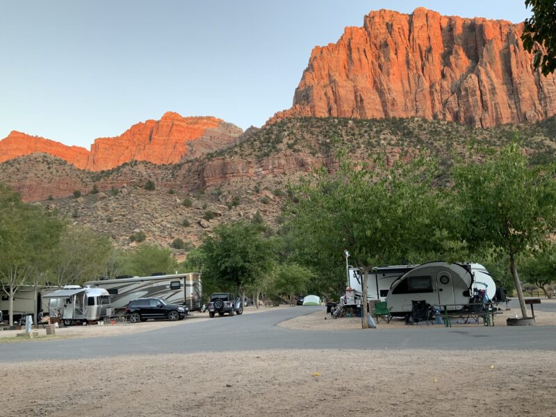 An RV campground outside of Zion National Park with looming red mountains in the background