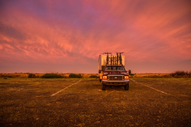An trailer and truck parked in a lot at sunset