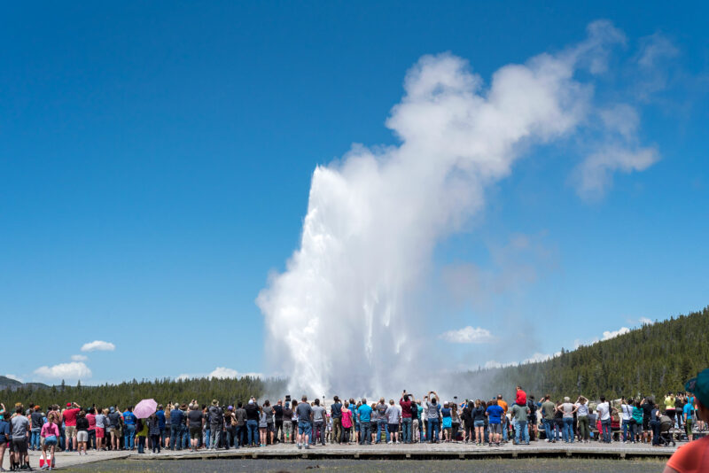 People standing around Old Faithful at Yellowstone National Park