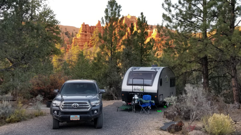 Truck and teardrop camper parked at campsite in canyons