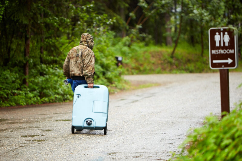 Person rolling black tank caddy through campground