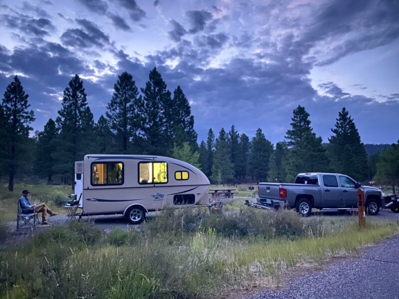 Small trailer parked at campsite in wooded area