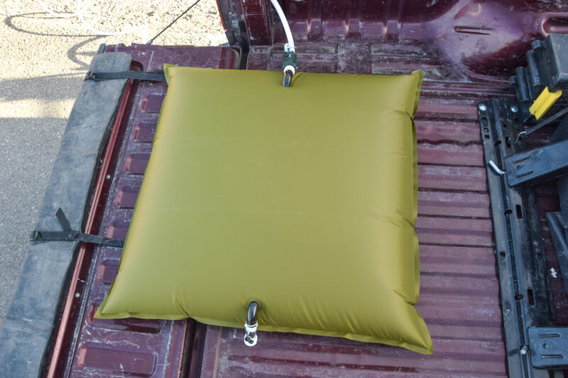 A filled up 30-gallon water storage bag in a truck bed