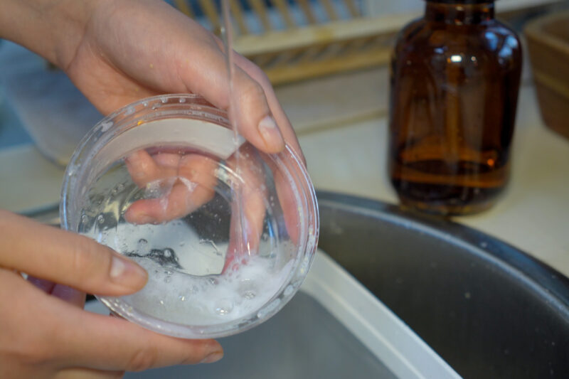 Plastic being washed in a sink under running water